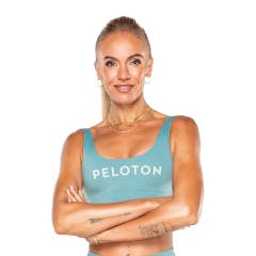 Headshot of Peloton instructor Becs Gentry. She's wearing a light blue Peloton two-piece workout outfit and smiling with her arms crossed.